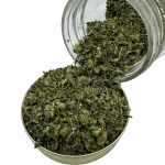 Close-up of Rockstar Shake cannabis blend in a metal tin with glass jar tipped over