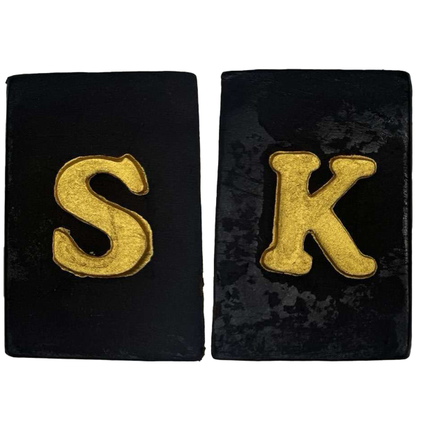 Two slabs of Strawberry Kush Hash with gold-embossed ‘S’ and ‘K’ letters on a dark, premium hash surface.