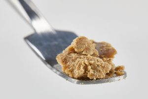 Light golden hash crumble placed on a metal dab tool, ready for consumption.